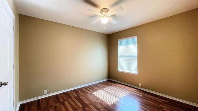an empty room with windows and ceiling fan