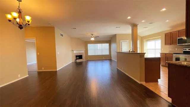 a view of a big room with wooden floor and a kitchen