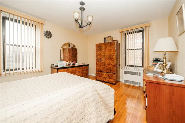 a spacious bedroom with a bed a dresser and a large window