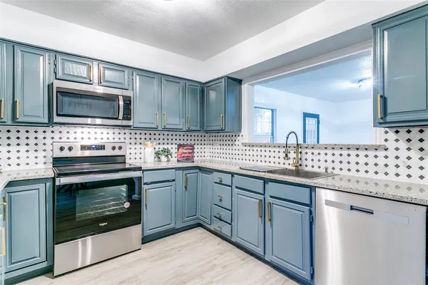 a kitchen with granite countertop cabinets stainless steel appliances and a sink
