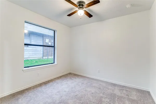 an empty room with a window and a ceiling fan