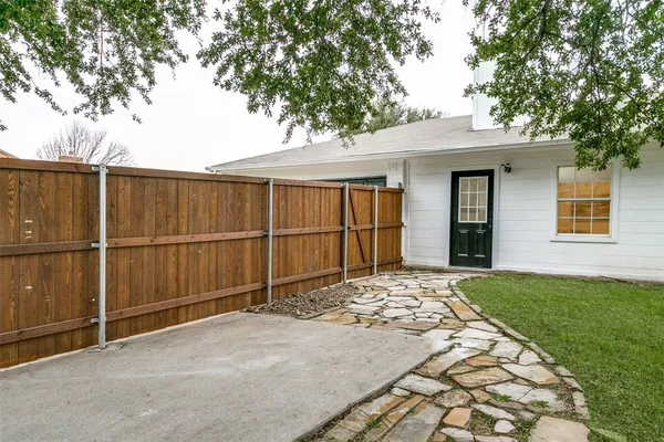 a backyard of a house with plants and large tree