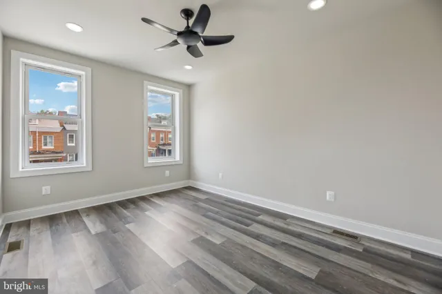 a view of an empty room with a window and wooden floor