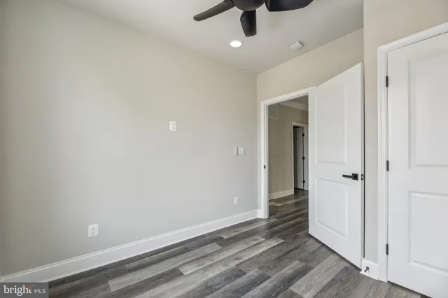 an empty room with wooden floor and ceiling fan