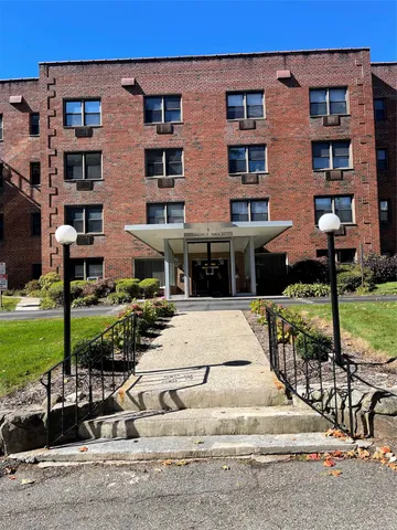 a front view of a building with a garden and plants