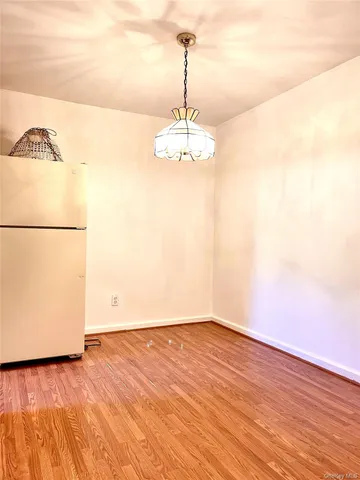 a view of a room with wooden floor and a refrigerator
