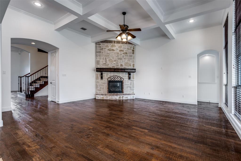 900 Jessica Lane Prosper, TX 75078 - Photo 11 of 40 Unfurnished living room with arched walkways, coffered ceiling, beamed ceiling, stairs, and a fireplace