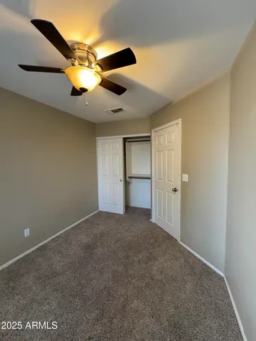 a view of an empty room and chandelier fan