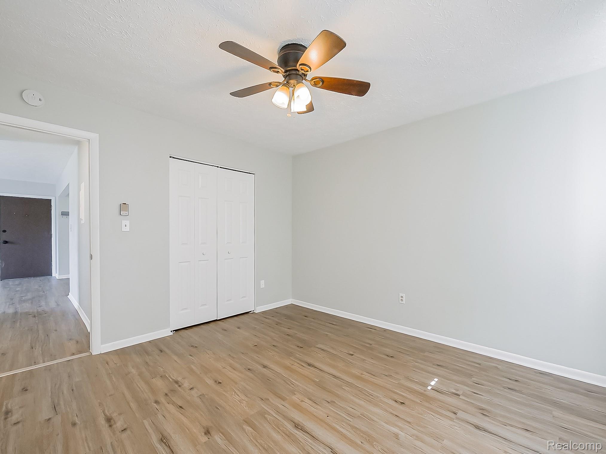 125 East Van Riper Road, Unit 7 Fowlerville, MI 48836 - Photo 17 of 26 Unfurnished bedroom with light wood-style floors, a closet, and ceiling fan