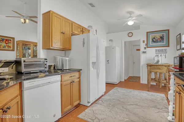 a kitchen with stainless steel appliances granite countertop a stove a sink dishwasher and a refrigerator with wooden floor