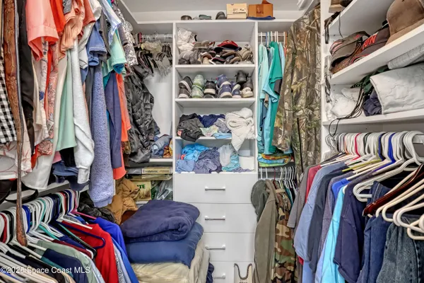 a view of walk in closet with clothes and shoes