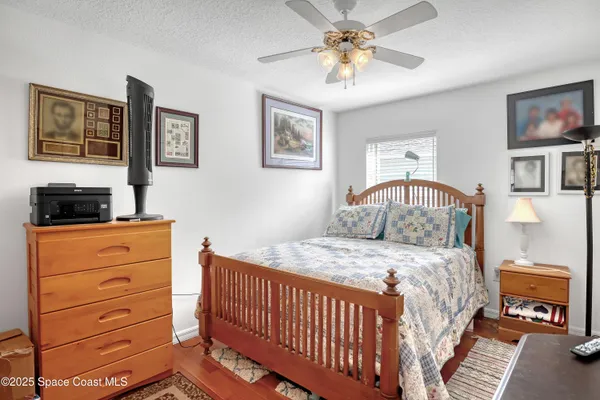 a bedroom with a bed a dresser and painting on the wall