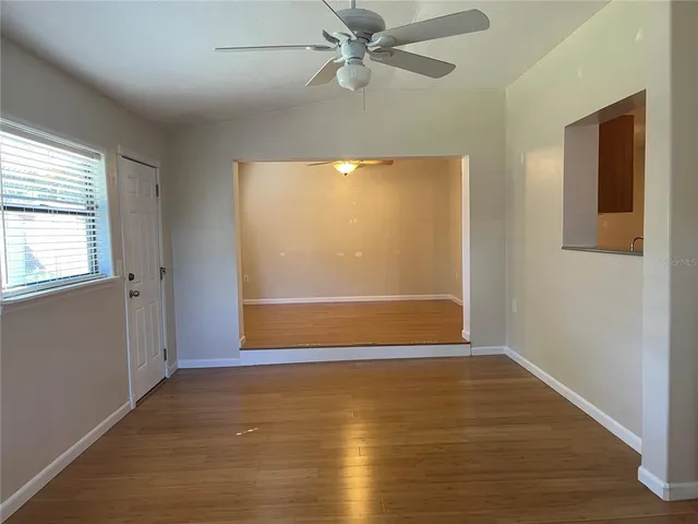 a view of empty room with wooden floor and fan