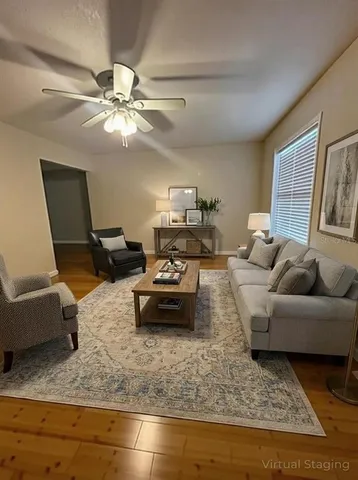 a view of an empty room with wooden floor and a chandelier fan