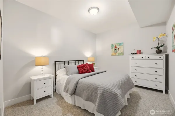 a bedroom with a bed and a lamp on dresser