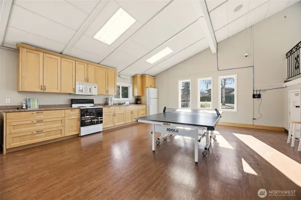 a large white kitchen with stainless steel appliances granite countertop a stove a sink dishwasher and white cabinets with wooden floor