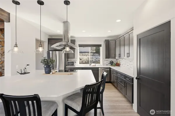 a kitchen with kitchen island a appliances dining table chairs and a wooden floor