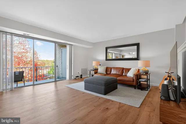 a living room with furniture two large window and a flat screen tv