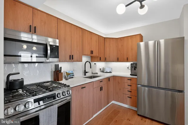 a kitchen with stainless steel appliances a refrigerator a sink and wooden cabinets