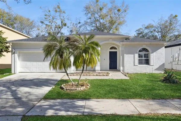 a front view of a house with a garden and palm trees