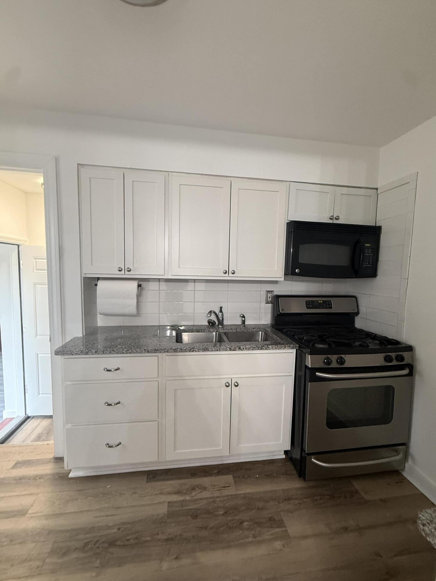 541 Chase Street Gary, IN 46404 - Photo 8 of 13 a kitchen with granite countertop a sink and a stove top oven with white cabinets