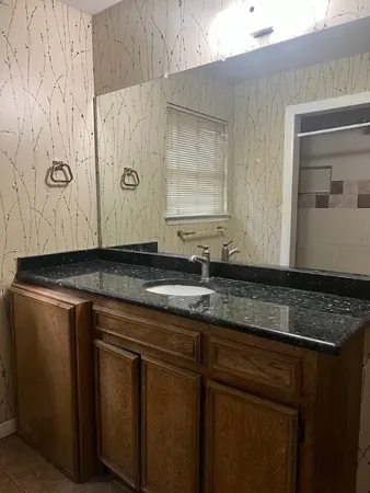 a bathroom with a granite countertop sink and a mirror