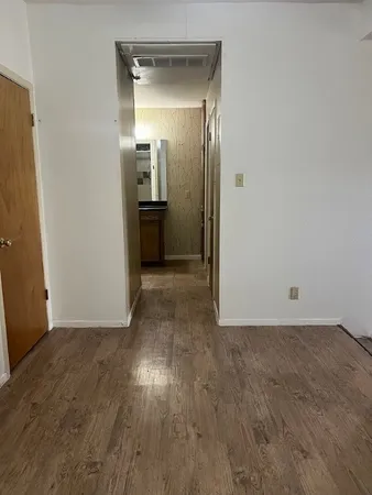 a view of a hallway with wooden floor and a bathroom