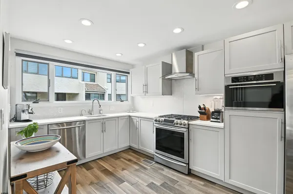 a kitchen with stainless steel appliances granite countertop a stove and white cabinets