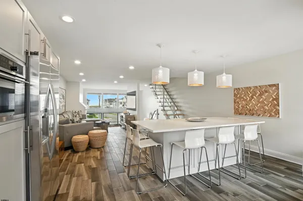 a kitchen with stainless steel appliances granite countertop a stove a refrigerator a oven and white cabinets with wooden floors