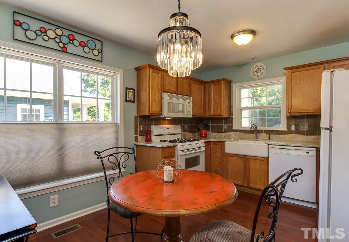 225 Cooke Street Raleigh, NC 27601 - Photo 7 of 24 a kitchen with stainless steel appliances granite countertop a stove a sink dishwasher a dining table and chairs with wooden floor