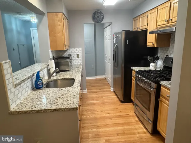 a kitchen with granite countertop kitchen island stainless steel appliances a refrigerator sink stove microwave and cabinets