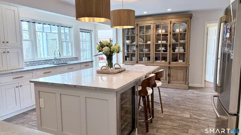 a kitchen with stainless steel appliances granite countertop a table chairs in it and wooden floors