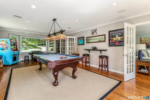 a living room with furniture pool table and wooden floor