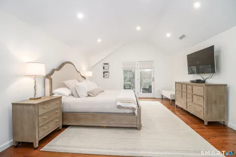 a bedroom with bed and a flat tv screen on dresser