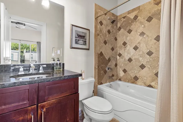 a bathroom with a granite countertop toilet a sink a mirror a bathtub and shower