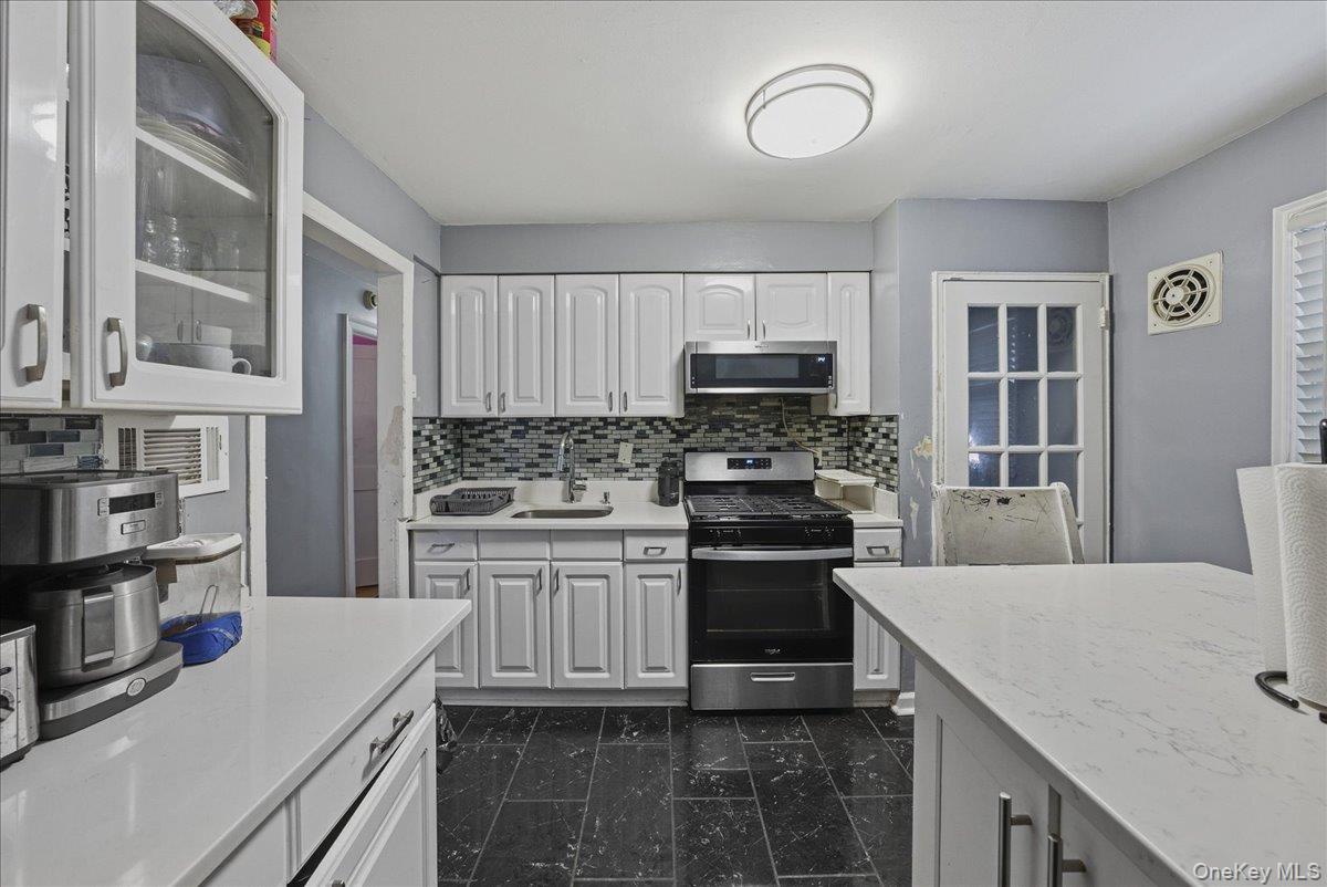 128-66 238th Street Queens, NY 11422 - Photo 8 of 25 a kitchen with stainless steel appliances a stove a sink and a refrigerator
