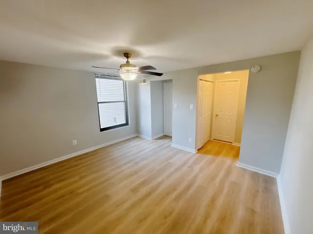a view of empty room with wooden floor and fan