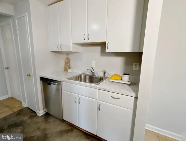 a kitchen with white cabinets and sink