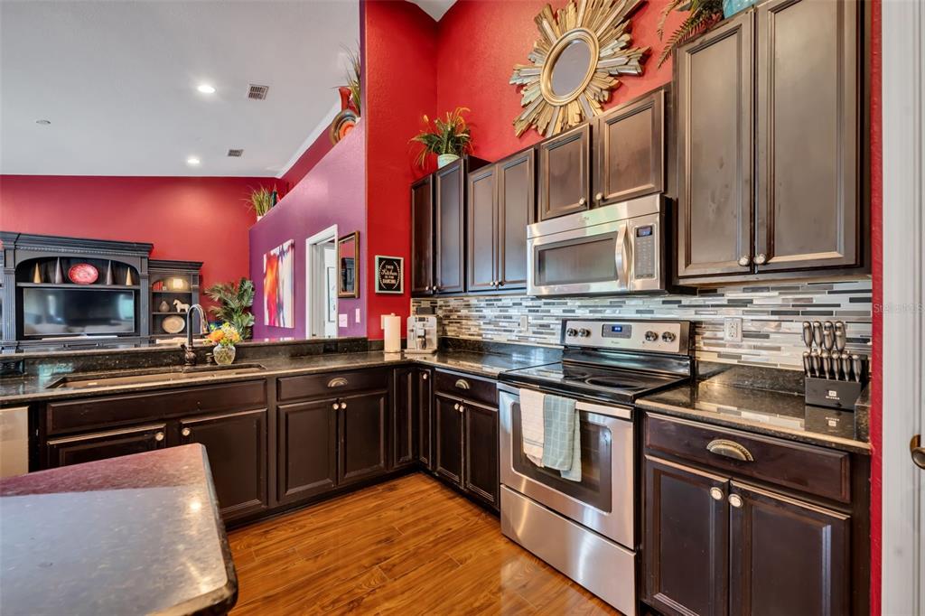 4946 Northeast 124th Road Oxford, FL 34484 - Photo 22 of 69 a kitchen with stainless steel appliances granite countertop a stove a sink and a microwave