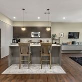 a kitchen with stainless steel appliances granite countertop a stove a sink a refrigerator and a dining table with wooden floor