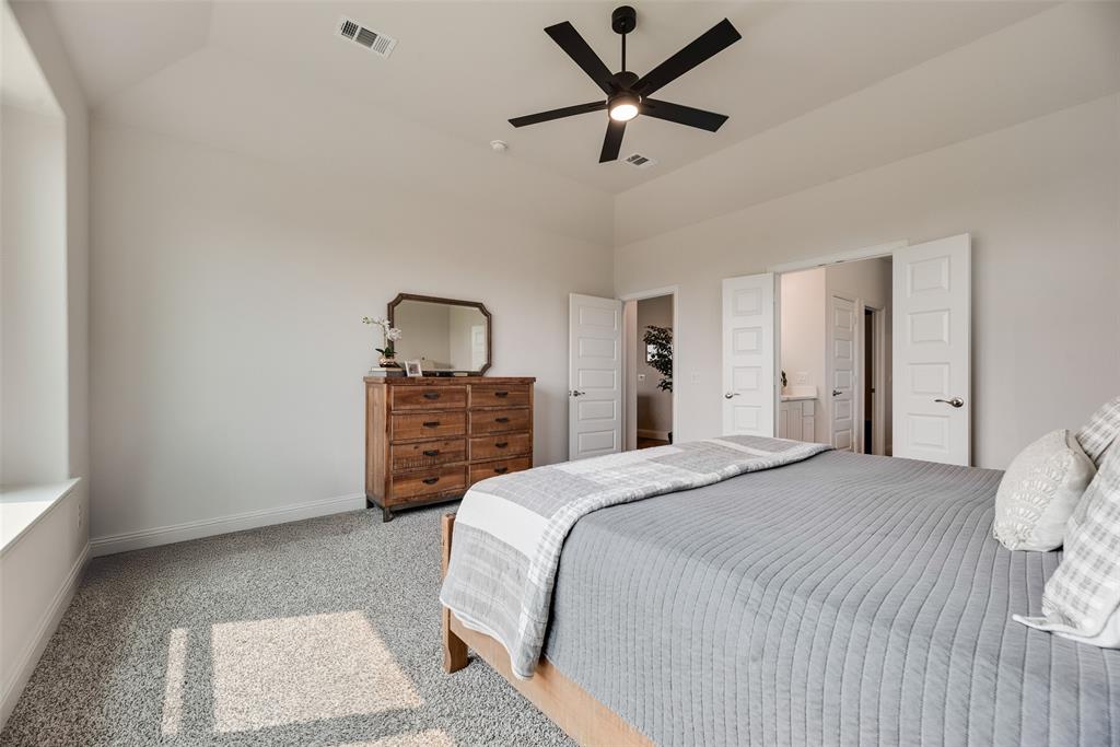 645 Mb Way South Pilot Point, TX 76258 - Photo 18 of 37 Spacious primary suite with a vaulted ceiling, abundant natural light, and oversized windows overlooking the backyard.