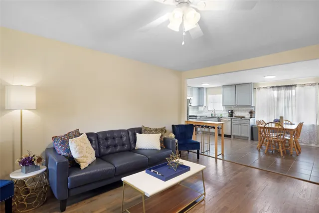 a living room with furniture a chandelier and a dining table with wooden floor