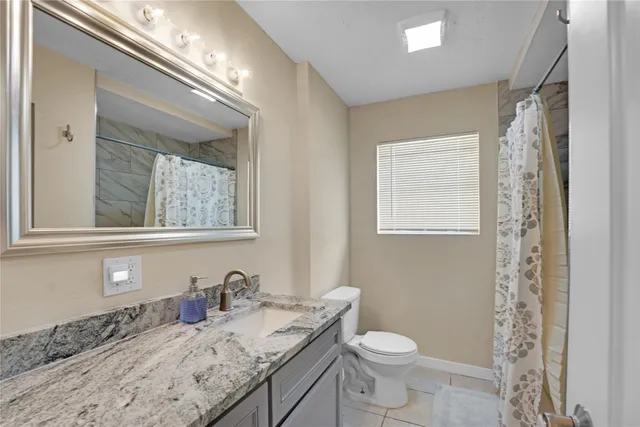 a bathroom with a granite countertop toilet a sink and a mirror