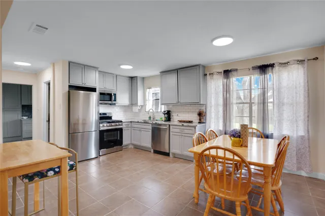 a kitchen with stainless steel appliances granite countertop a stove a refrigerator a sink dishwasher a dining table and chairs with wooden floor