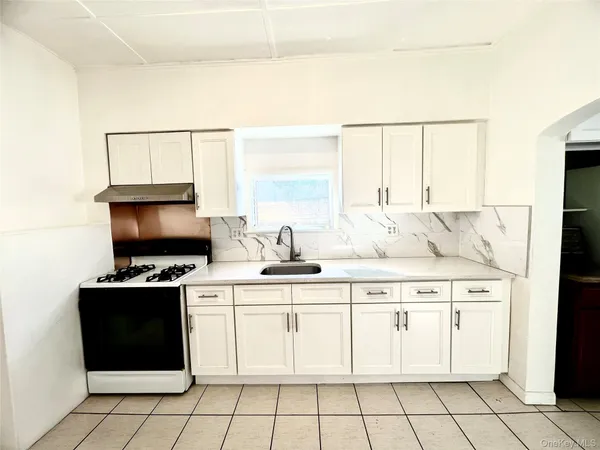 a kitchen with a stove a sink and white cabinets
