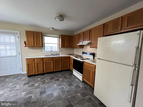 a kitchen with granite countertop a refrigerator a sink a stove a microwave and island