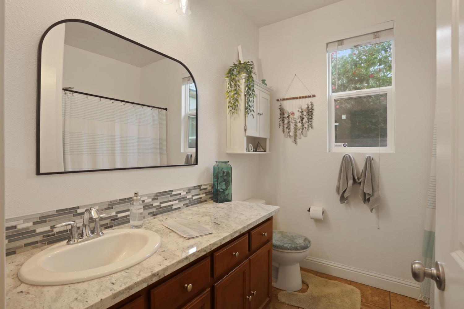 1091 Alba Street Manteca, CA 95337 - Photo 11 of 37 a bathroom with a granite countertop sink a toilet and a mirror
