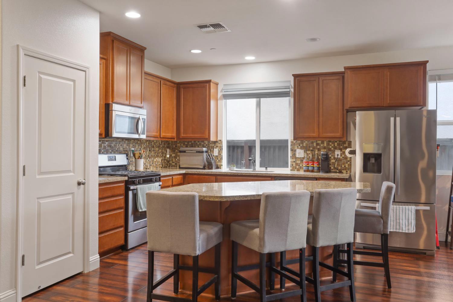 1091 Alba Street Manteca, CA 95337 - Photo 13 of 37 a kitchen with stainless steel appliances granite countertop a stove a refrigerator a kitchen island and chairs with wooden floor