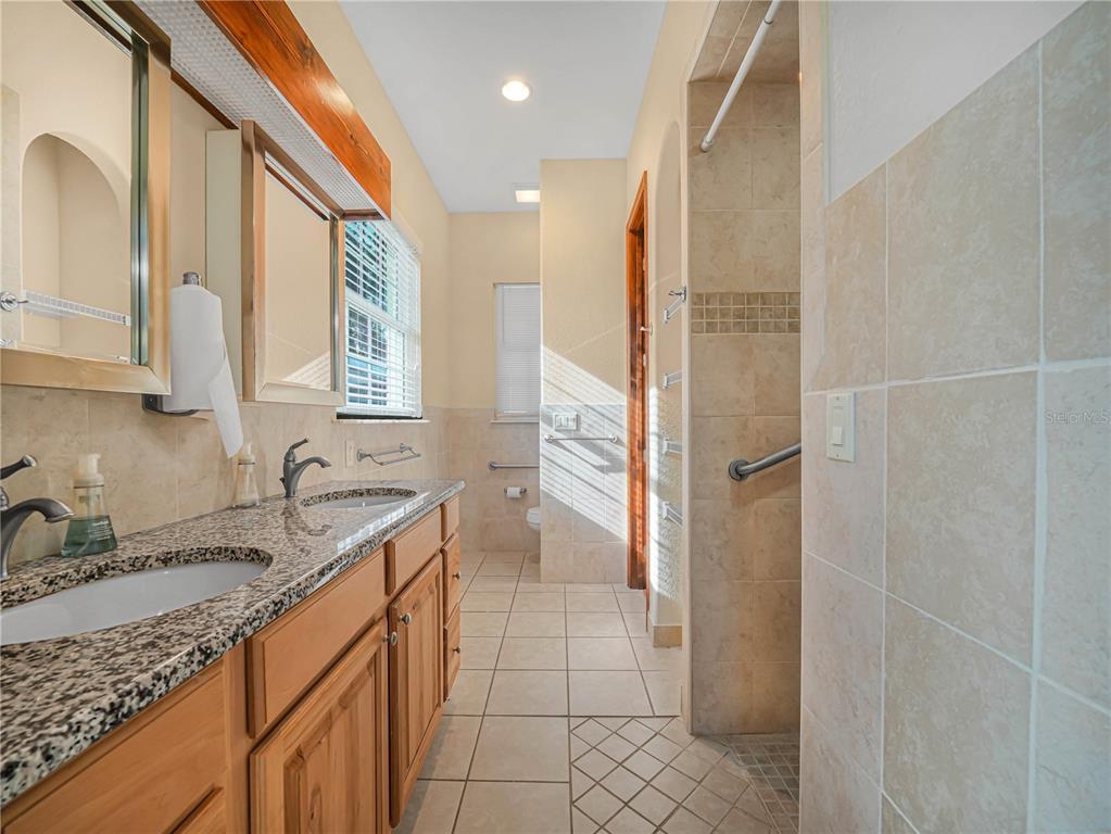 100 Reedy Creek Drive Frostproof, FL 33843 - Photo 13 of 36 a bathroom with a granite countertop sink a mirror and a shower
