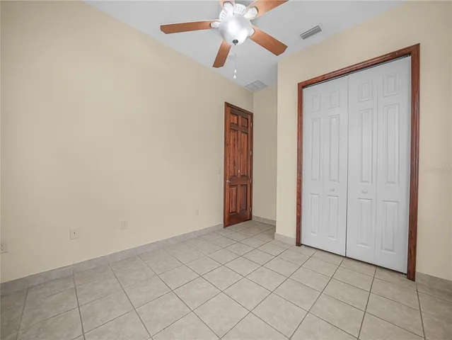a view of an empty room and chandelier fan